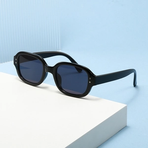 Retro oval sunglasses with thick black frames and silver studs on white podium