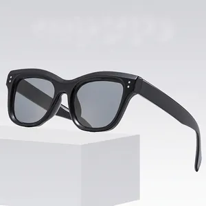 Classic black square sunglasses with silver rivets on a minimalist white platform