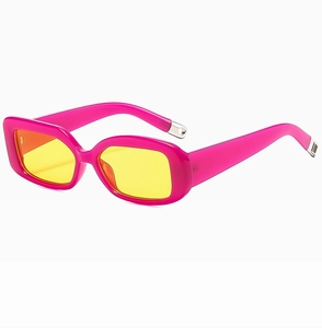 Detail of retro rectangle sunglasses with pink frames and yellow lenses and metal tips