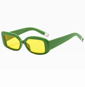 Detail of trendy green thick frame sunglasses featuring transparent yellow lenses and metal accents