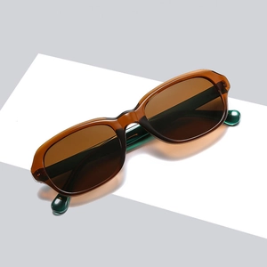 Lunettes de soleil rétro ovale avec monture ambre et verres foncés sur socle blanc