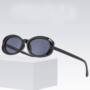 Lunettes de soleil ovales ajourées avec verres gris foncé sur support géométrique blanc