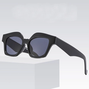 Lunettes de soleil rétro à monture carrée noire et verres foncés sur socle blanc