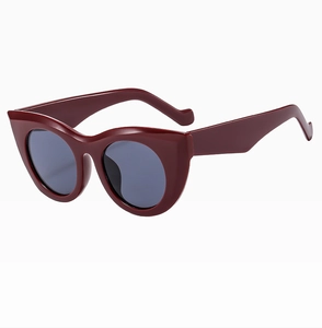 Detail of wine red cat eye sunglasses with glossy frame and dark grey lenses