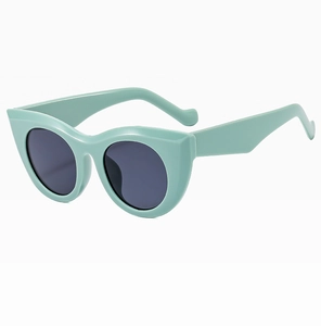 Detail view of mint green cat-eye sunglasses with thick frames and dark UV lenses