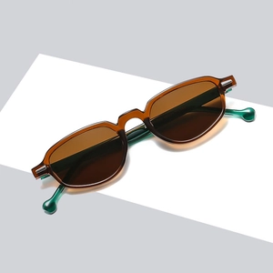Lunettes de soleil rétro avec monture ambre et branches vertes sur un piédestal