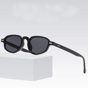 Lunettes de soleil ovales noires rétro avec détails argentés sur support blanc