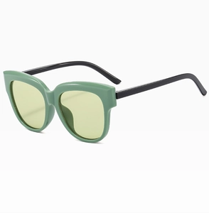 Détail de lunettes de soleil œil-de-chat rétro avec monture verte et verres teintés jaunes