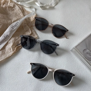 Trois paires de lunettes de soleil pour enfants aux tons neutres sur fond blanc