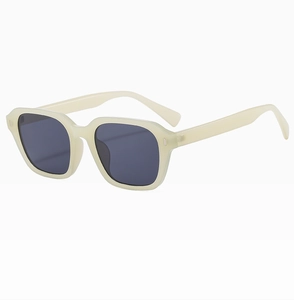 Close-up of retro cream rectangle sunglasses with thick frames and dark grey lenses