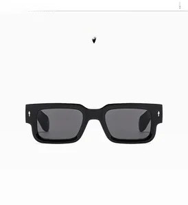 Close-up of thick rectangular sunglasses with glossy black frame and dark grey lenses