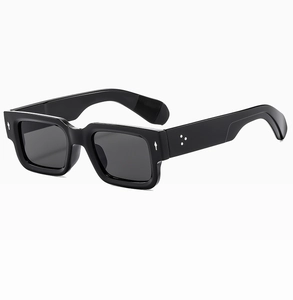 Detail of square black frame sunglasses featuring three metal rivets and grey lenses