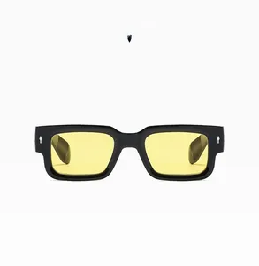 Close-up of retro square sunglasses with black frame, yellow lenses and silver rivets