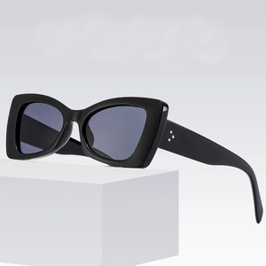 Black butterfly cat-eye sunglasses with silver dot accents on a white display pedestal