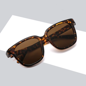 Classic tortoiseshell square sunglasses with brown lenses on a geometric background