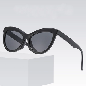 Fashionable black cat eye sunglasses with dark lenses on a white geometric stand