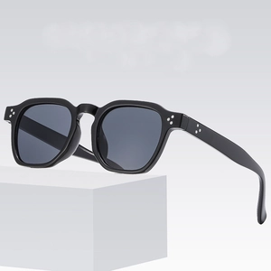 Vintage oval black sunglasses with silver rivet accents on a modern white pedestal stand