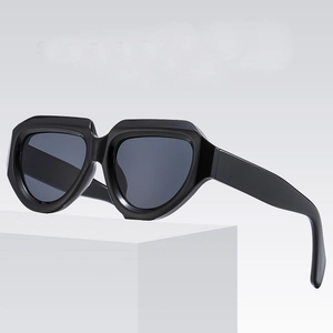 Modern irregular black geometric sunglasses with grey lenses on a minimalist white stand