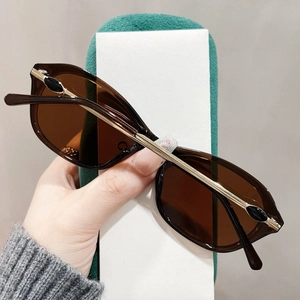 Detail einer braunen Cat-Eye-Sonnenbrille mit goldenen Metallbügeln und Juwelen-Akzenten