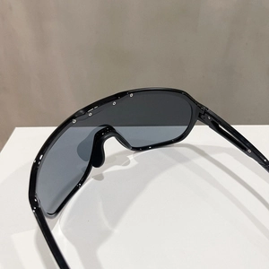 Detail of black sports sunglasses featuring a large shield lens and silver stud accents