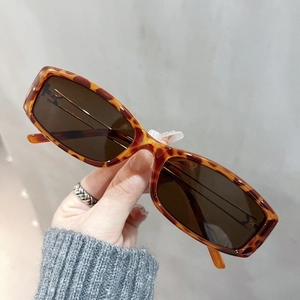 Detail of hand holding vintage tortoiseshell TR90 square frame glasses with brown lenses