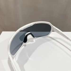 Detail of bright white sports sunglasses with dark grey lenses and black nose pads
