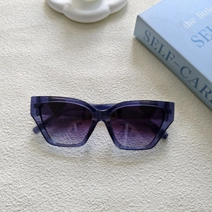 Détail de lunettes de soleil œil-de-chat violettes avec verres dégradés sur fond texturé