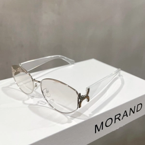Detail of gold metal oval frame sunglasses with S-shaped hinges and clear resin temples
