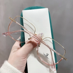 Détail de lunettes anti-lumière bleue roses avec branches dorées sur velours vert