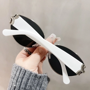 Close-up of white cat-eye sunglasses with thick frames and silver hollow metal temple detail