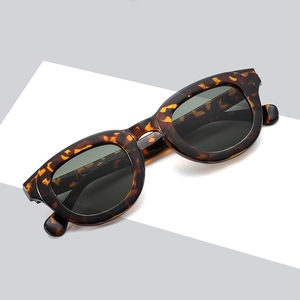 Retro tortoiseshell sunglasses with dark lenses on a minimalist grey geometric background