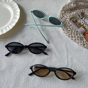 Detailed flat lay of vintage oval sunglasses in green, black, and tea-colored lenses