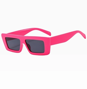 Detail der neonpinken rechteckigen Sonnenbrille mit dunkelgrauen Gläsern im Y2K-Stil