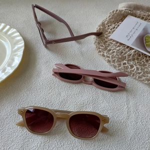 Macro shot of retro oval sunglasses with metal rivets on textured beige background