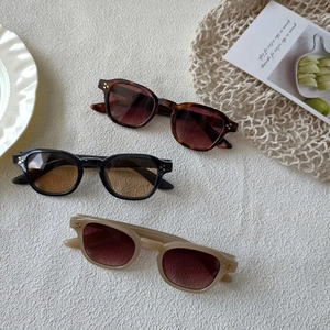 Close-up of retro small frame sunglasses in tortoise, black, and beige with metal studs