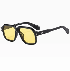 Detail of square vintage sunglasses with black frames, yellow lenses, and silver rivets