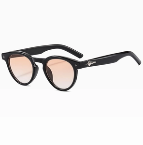 Detail view of oval black sunglasses with amber lenses and silver star metal accents