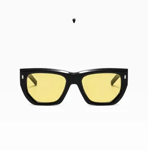 Detail of oversized black polygon sunglasses with yellow lenses and silver rivets