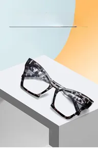 Close-up of cat-eye eyewear frames with dark grey tortoise texture on a geometric display
