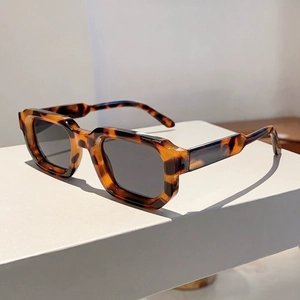 Retro tortoise shell rectangle sunglasses with dark lenses on a minimalist white stand