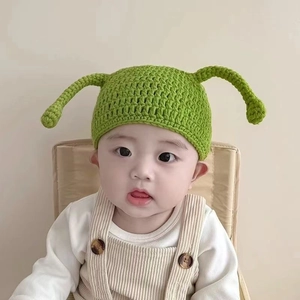 Detail of green baby knit hat with cartoon antennae showing soft wool texture