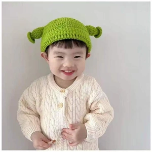 Close-up of baby wearing a green Shrek-style knitted hat with 3D ears and chin straps