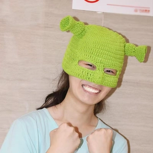 Close-up of green hand-knitted Shrek style balaclava with funny horn ears for winter warmth
