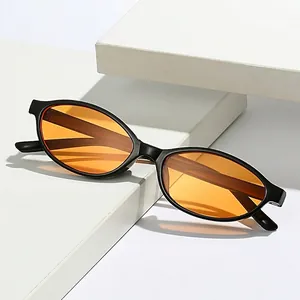 Chic oval sunglasses with black matte frame and orange tinted lenses on geometric prop