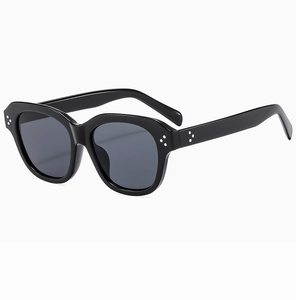 Detail of glossy black wave-frame sunglasses with silver decorative triple studs