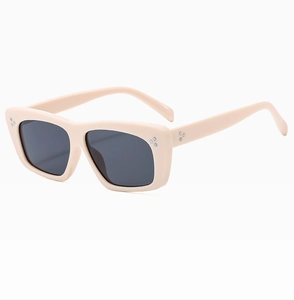Detailed close-up of cream retro sunglasses frame featuring silver three-dot rivet accents