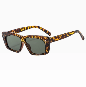 Close-up of tortoiseshell sunglasses featuring square frames and silver triple-dot accents