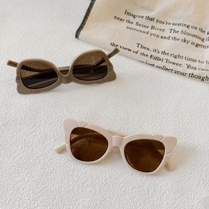 Stylish cat-eye sunglasses in cream and olive green with textured frames on white surface