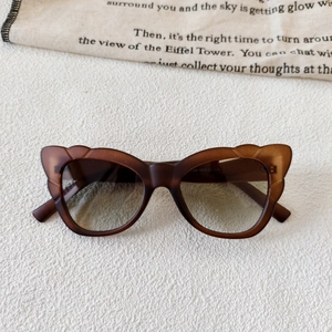 Detail view of butterfly cat eye sunglasses with brown matte frames and gradient lenses
