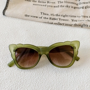 Detail of olive green cat-eye sunglasses with gradient brown lenses and metal hinge
